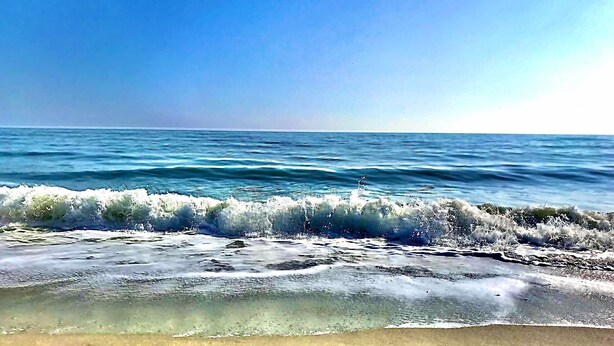 A beach with waves crashing onto the shore under a clear sky. - Oak Island Beach House -- Sand, Sun, and Fun Just Steps Away!! (Oak Island)