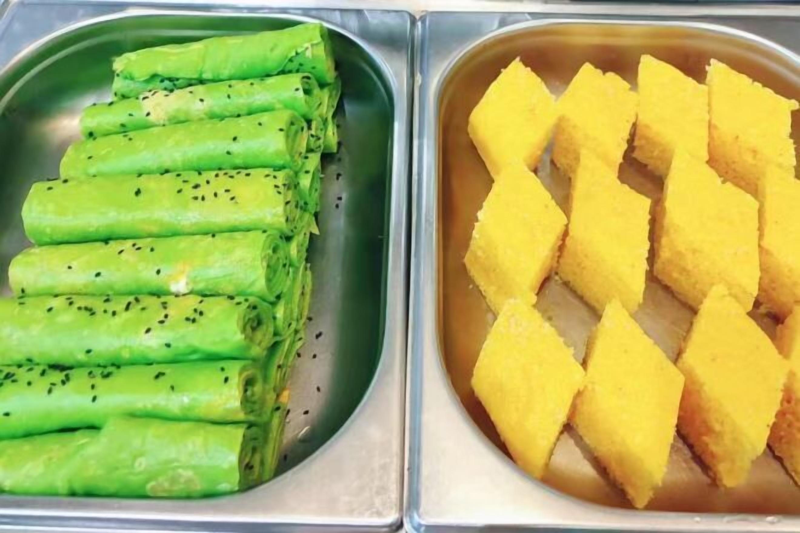 Two metal trays, one with rolled green vegetables and the other with yellow cubes.