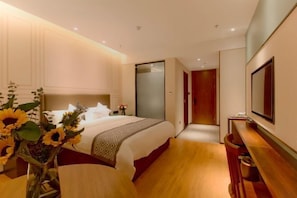 Una camera d'albergo moderna con un letto grande, un comodino, uno specchio e una panca in legno.