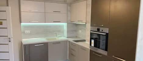 A modern kitchen with a central island, built-in oven, and a chandelier.
