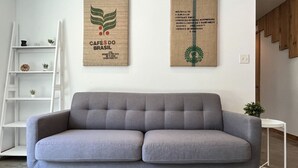 A grey sofa in a living room with a white ladder and shelves, and two wall-mounted certificates. - Sun Filled Haus: Private Entry, Yard, Carport (Austin)