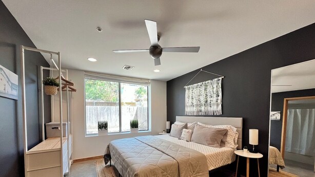 A modern bedroom with a bed, bedside table, and a ceiling fan. - Sun Filled Haus: Private Entry, Yard, Carport (Austin)