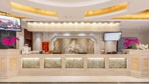 A reception area with a marble counter, a television, and a digital screen. - Yushengyuan International Hotel (Jingyang)