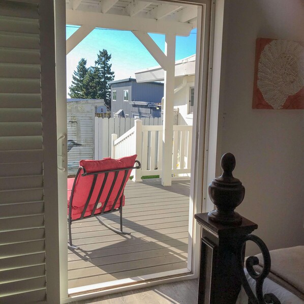 A covered outdoor area with a wooden deck, a white fence, and a red chair. - Adventure & Relax "Lee's Harbor Inn Unit B" (Brookings)