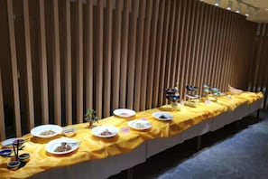 A buffet table with various dishes and a yellow tablecloth, set against a wooden backdrop. - Yingbin Hotel (Linzhang)