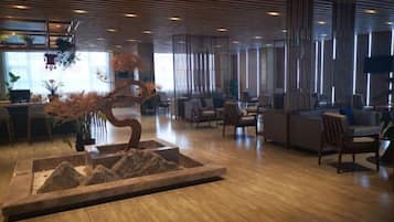 Un hall moderno con suelo de madera, zona de estar y un elemento decorativo central.