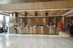 A reception desk with a modern design, a digital screen, and a uniformed staff member.