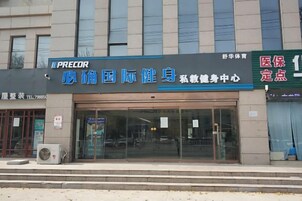 Un edificio con un amplio acceso de vidrio, un letrero que dice 'PRECOR' a la izquierda y otro que indica 'Seguro Médico' a la derecha.