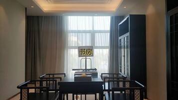 A room with a dining table, chairs, a window with curtains, and a sign with Chinese characters.