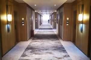 Un pasillo de hotel con paredes de madera, suelo alfombrado y luminarias fijadas a la pared.