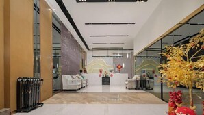 A modern lobby with a reception desk, seating area, and a decorative tree. - Kignmar Fashion Hotel (Luohu Sungang Subway Station) (Shenzhen)