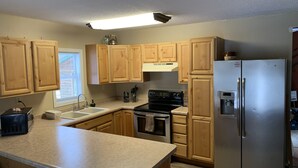 A kitchen with wooden cabinets, a stainless steel refrigerator, a black stove, and a countertop.