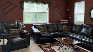 A living room with a leather sofa, a coffee table, a fireplace, and a ceiling fan.
