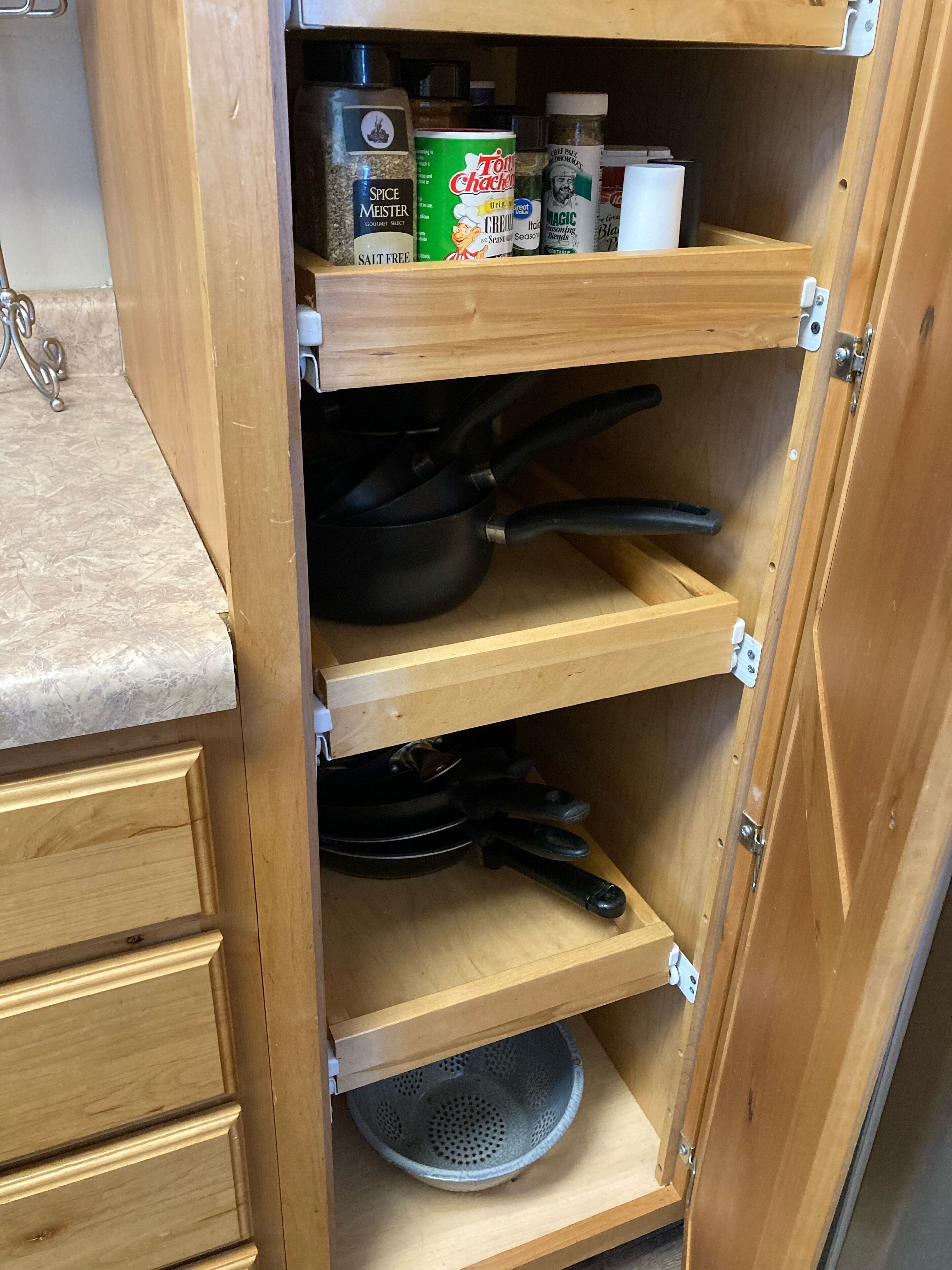 Un meuble en bois doté d’étagères contenant des ustensiles de cuisine, comme un pot à épices, une boîte de crème et une passoire.