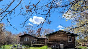 Two wooden cabins with a picnic table and chairs in the foreground.