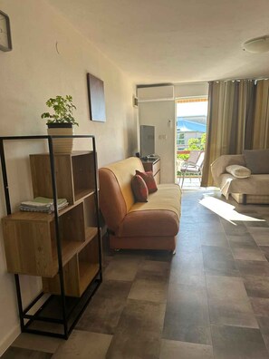 Un salon avec un canapé, une table basse, une bibliothèque et une plante en pot.
