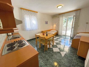 Cozinha compacta com área de refeições, uma cama e porta de vidro deslizante para o exterior.