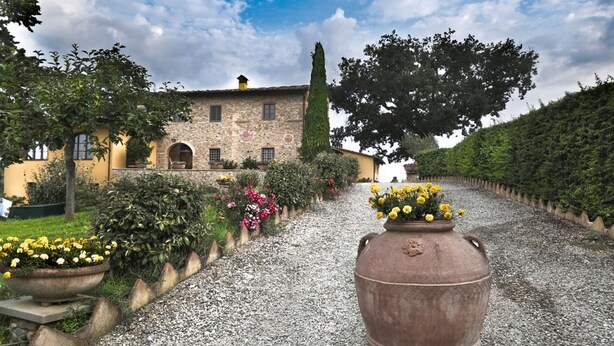 A stone building with a gravel path, potted plants, and a large vase with flowers. - La Quercia, apartment with garden for 6/8 people  in the heart of Chianti (Montespertoli)