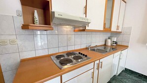 A kitchen with a gas stove, sink, and white cabinets. - Holiday apartment with outdoor swimming pool (Jadranovo)
