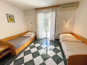 A room with two single beds, a small table, and a window with curtains.