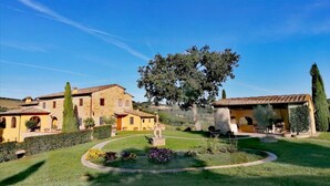 Une propriété située à la campagne, avec des bâtiments en pierre, un grand arbre et un jardin bien entretenu.