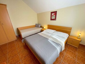 Cozy retreat with a single bed and a smaller bed or daybed, featuring a wardrobe and nightstand with a lamp.