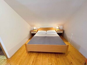 Habitación individual con una cama que tiene cabecera de madera, dos mesitas de noche con lámparas y piso de madera.