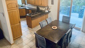 Une cuisine moderne avec des meubles en bois, un îlot central et un coin repas comprenant une table et des chaises.