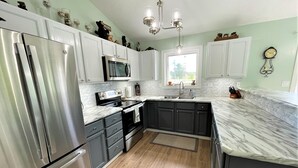 A modern kitchen with stainless steel appliances, dark cabinets, and a marble countertop. - Modern  • Attached garage • Dog friendly • ATV & Sled friendly (Ironwood)