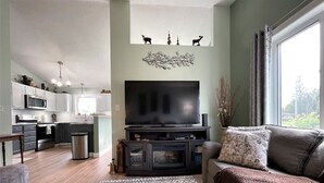 A modern living room with a flat-screen TV, a sofa, and a patterned rug. - Modern  • Attached garage • Dog friendly • ATV & Sled friendly (Ironwood)