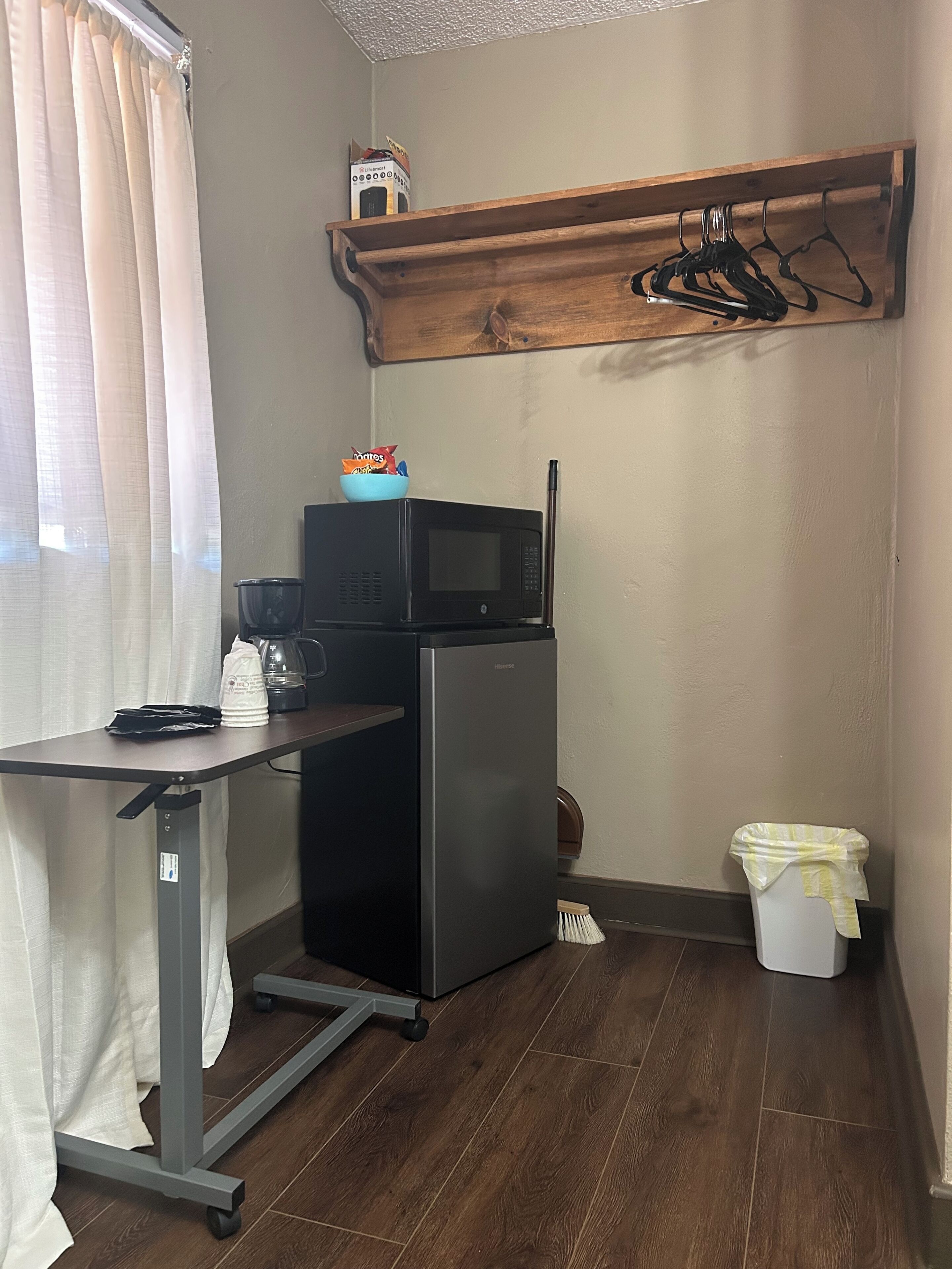 Una kitchenette compacta con refrigerador, microondas y cafetera sobre una mesita.
