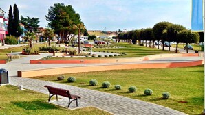 Un parque con un sendero pavimentado, bancos y setos recortados.