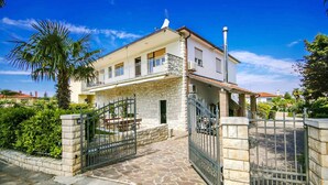 Una casa de dos pisos con fachada de piedra, un balcón y una entrada con reja.