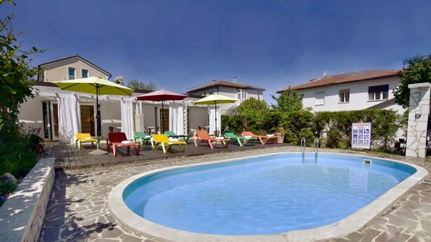A swimming pool with colorful lounge chairs and umbrellas, surrounded by stone walls and a clear blue sky. - Studio close to the sea, with pool and jacuzzi (Umag)