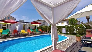 A pool area with a clear blue pool, surrounded by colorful lounge chairs and umbrellas. - Studio close to the sea, with pool and jacuzzi (Umag)