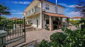 A two-story house with a stone facade, a balcony, and a brick fireplace. - Holiday apartment close to the sea, with pool and jacuzzi for 9 people (Umag)
