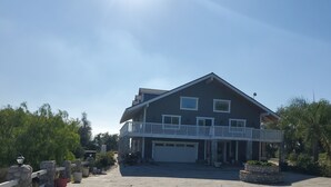 Een woonhuis met twee verdiepingen, een balkon, een garage en een pad van stenen dat naar de ingang leidt.