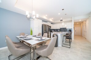 A modern kitchen with white cabinets, a central island, and a dining area with a table and chairs.