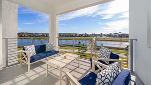 Ein Balkon mit Blick auf einen See und entfernte Gebäude, ausgestattet mit einer Couch, Stühlen und einem Tisch.
