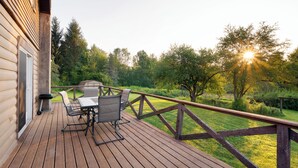 A wooden deck with a table and chairs, overlooking a grassy yard with trees and a wooden fence. - Elk Mountain Vacation Home on 21 Acres (Union Dale)