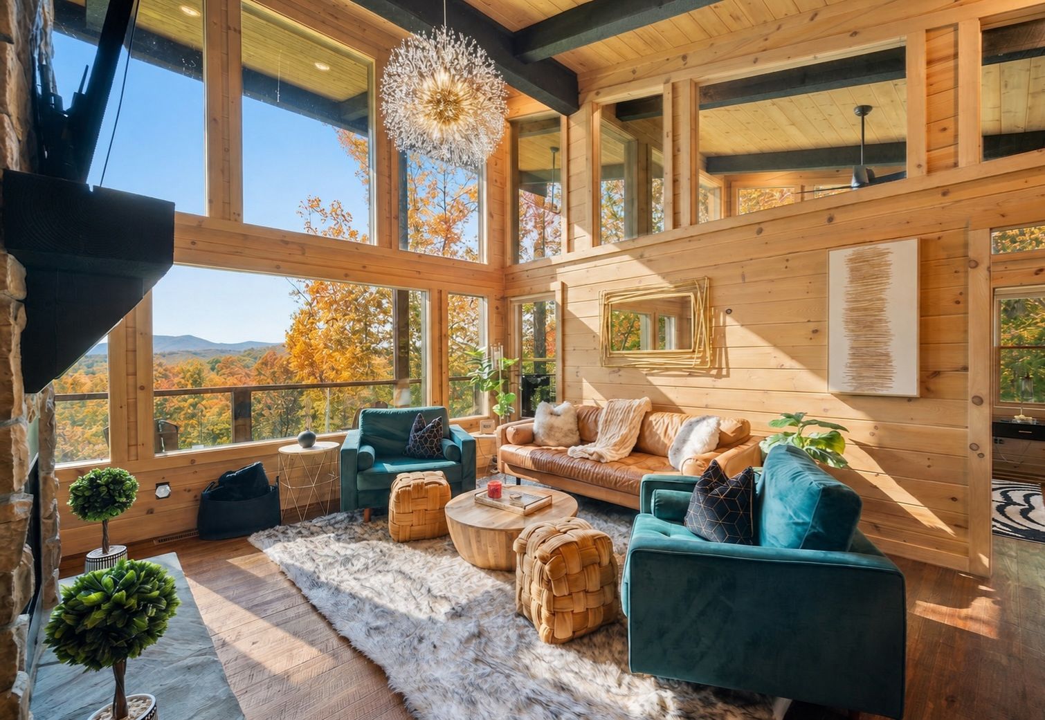 A spacious room with large windows, a cozy seating area with a sofa and chairs, a wooden ceiling, and a view of autumn trees.