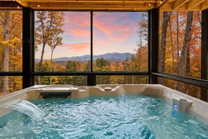 Ein Whirlpool mit Blick auf Herbstbäume und Berge.