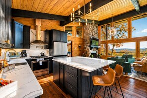 Una cocina moderna con una isla grande, electrodomésticos integrados y una pared decorativa de piedra.