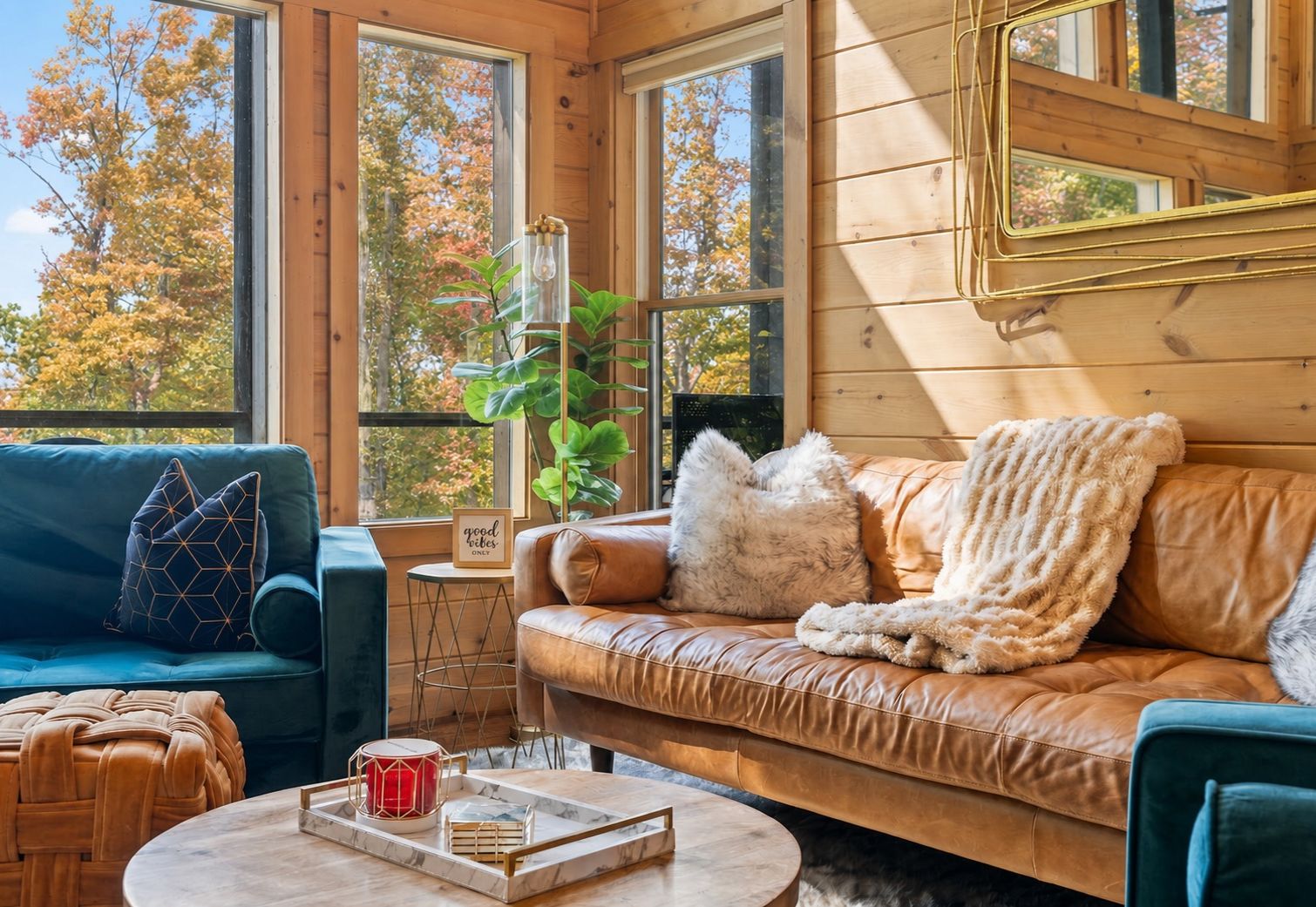 A cozy cabin interior with a leather sofa, a blue armchair, and a round coffee table.