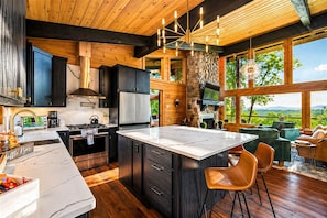 A modern kitchen with a large island, dark cabinetry, and a stone accent wall.