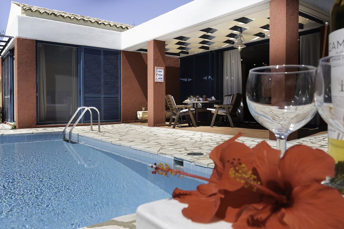 Ein Poolbereich mit freiem Blick auf den Pool, einem Tisch mit Stühlen und einer Weinflasche.