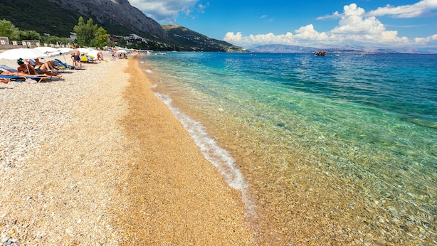 A pebble beach with clear water and a mountain in the background. - Barbati Beach Villas (Corfu)