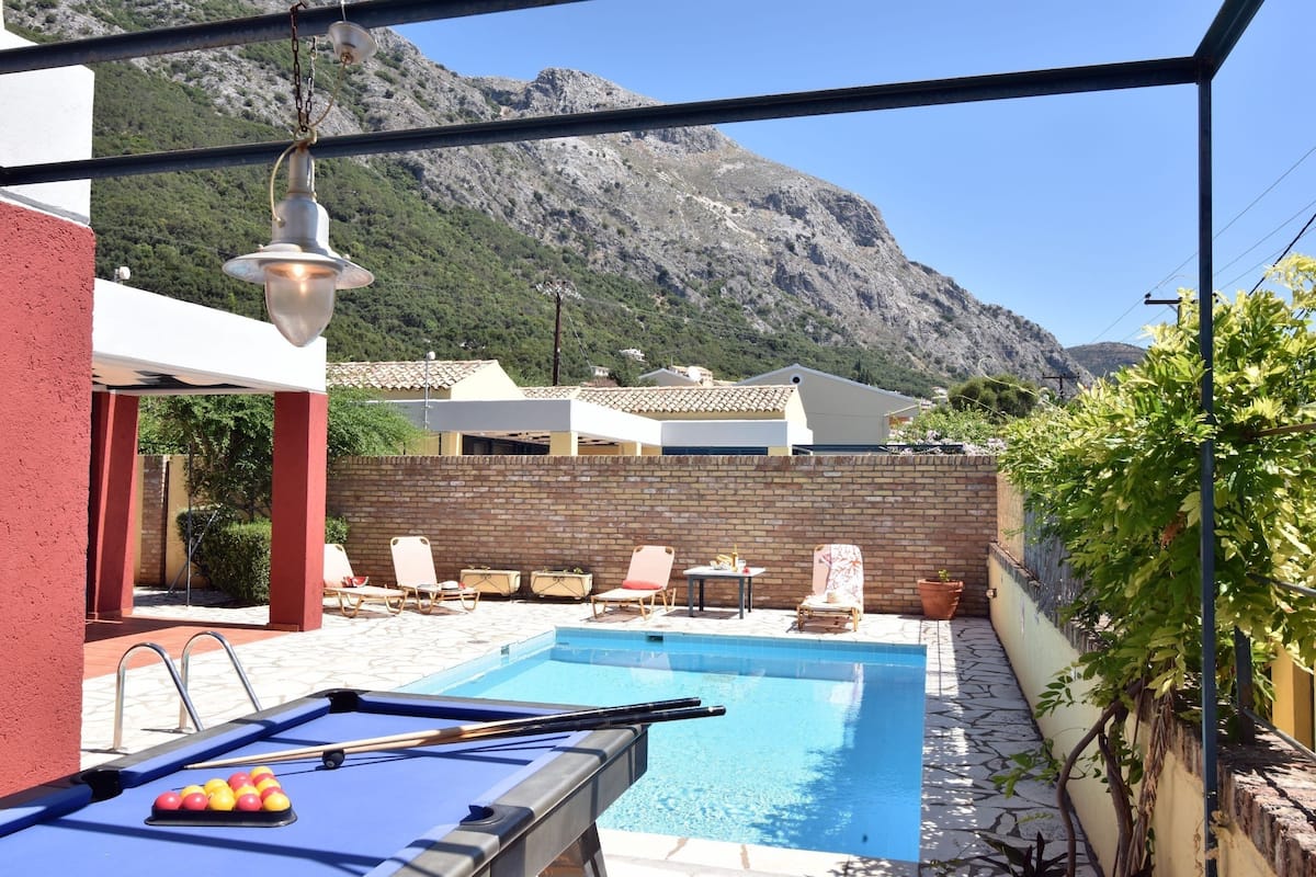 Ein Poolbereich mit Billardtisch, Liegestühlen und Bergblick.