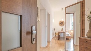 A modern hotel room with a wooden door, a large mirror, a round wall decoration, a bed, a nightstand, and a dresser. - Appartment Lissi a few steps from the centre of Merano (Meran)
