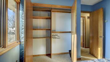 A bedroom with a built-in closet, a window, and a door leading to another room.
